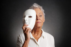 serious older woman revealing face behind mask